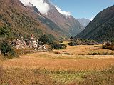 Manaslu 06 06 Lho The views now start to open up, but clouds obscured Manaslu and Manaslu North (7157m). I looked back at Lho (3180m), with the enormous mani wall on the left, and fields of barley in front. Note the electricity poles on the far right.